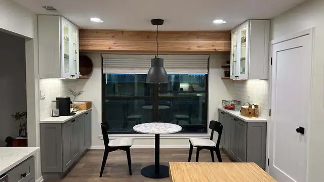 Small kitchen remodel with gray and white cabinets, a wood accent wall and a round breakfast table