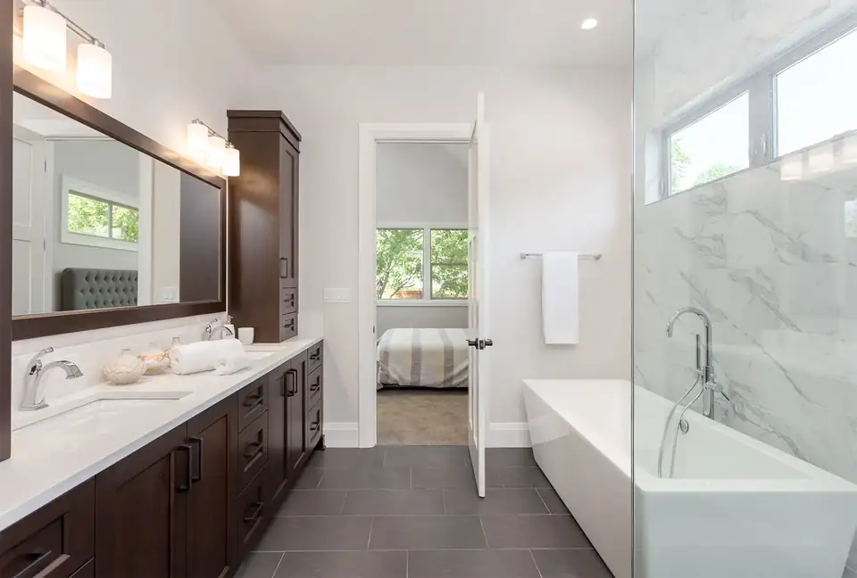 Bathroom remodeling San Antonio: primary bath with a dark wood double vanity, freestanding tub and glass shower with marble-look tile