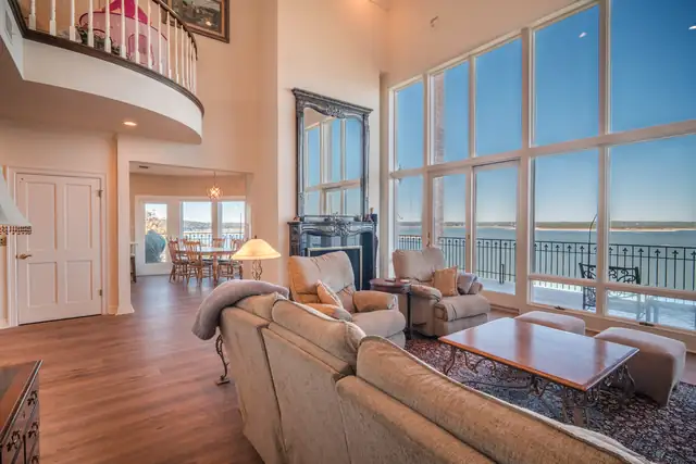 Open living area in a whole-home remodel by C&S Remodeling with wood-look floors and a two-story wall of windows