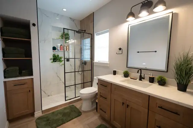 Bathroom remodel in San Antonio with a black-framed glass shower, marble-look wall tile and a wood shaker vanity