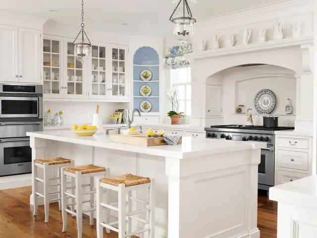 White kitchen remodel with glass-front upper cabinets, an arched range alcove, island seating and lantern pendants