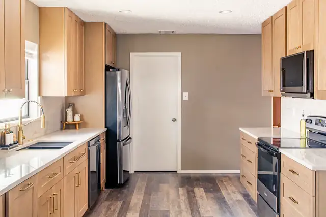 Kitchen remodel with natural maple cabinets, white quartz counters, stainless appliances and wood-look plank floor